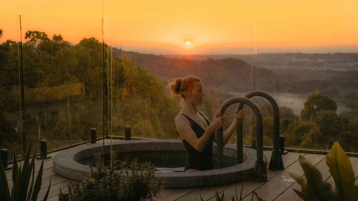 Guest relaxing in the plunge pool at sunset above the hinterland