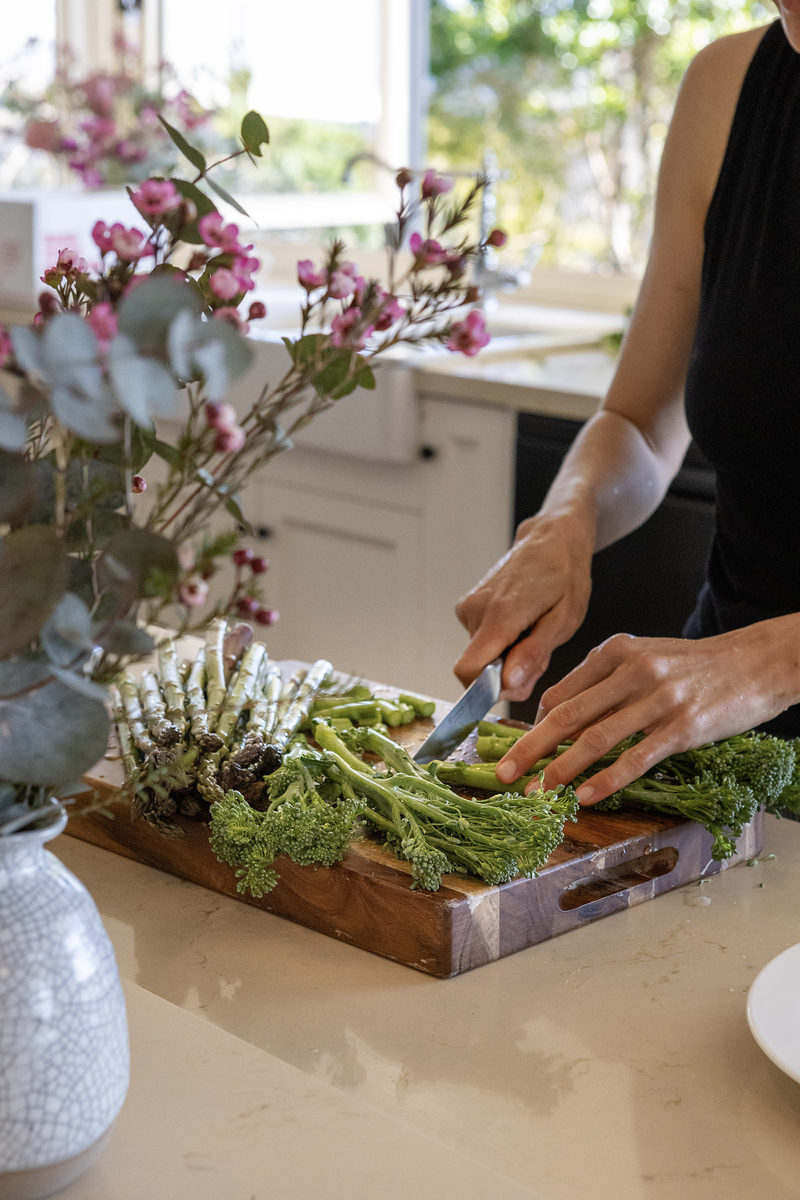 Preparing fresh produce beside a vase of wildflowers