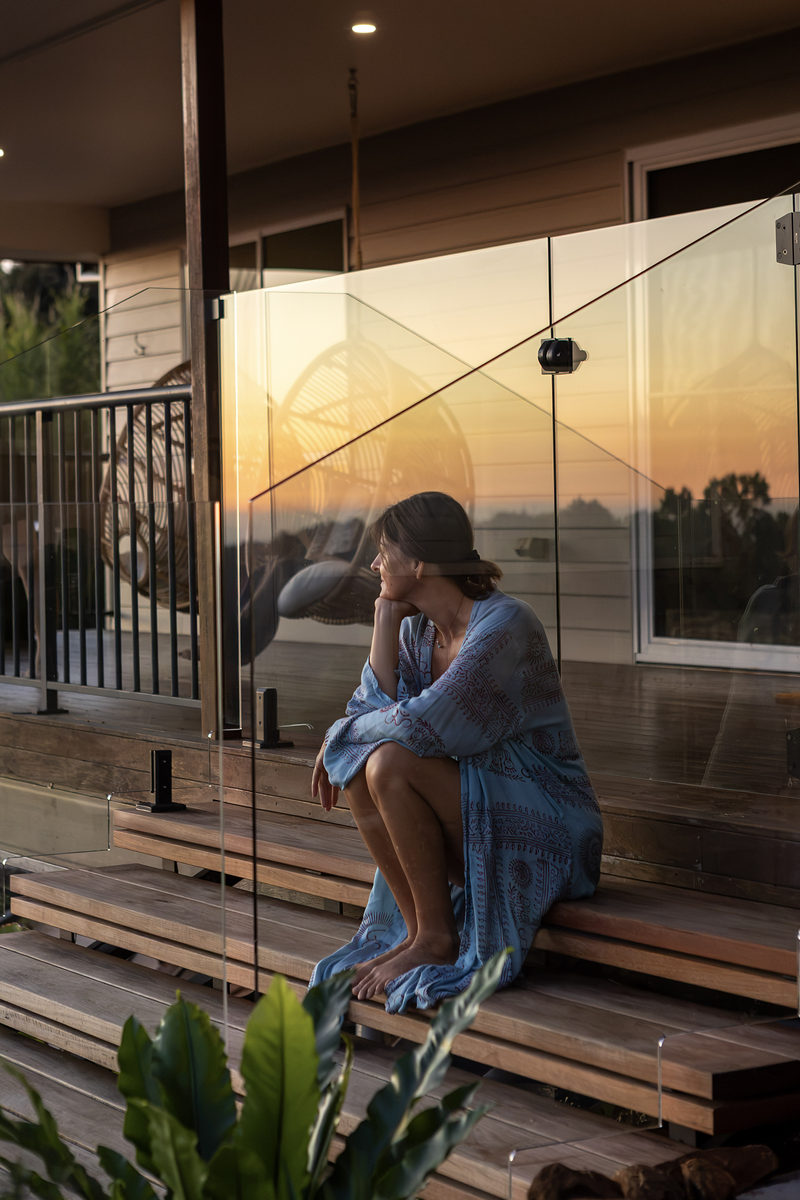 Guest sitting on the timber steps beneath the house at dusk