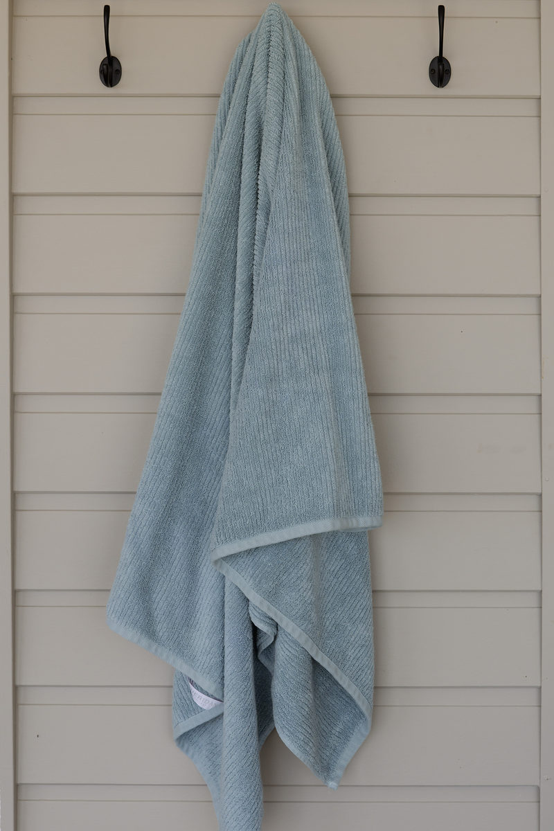 Soft aqua towel hanging on a timber wall