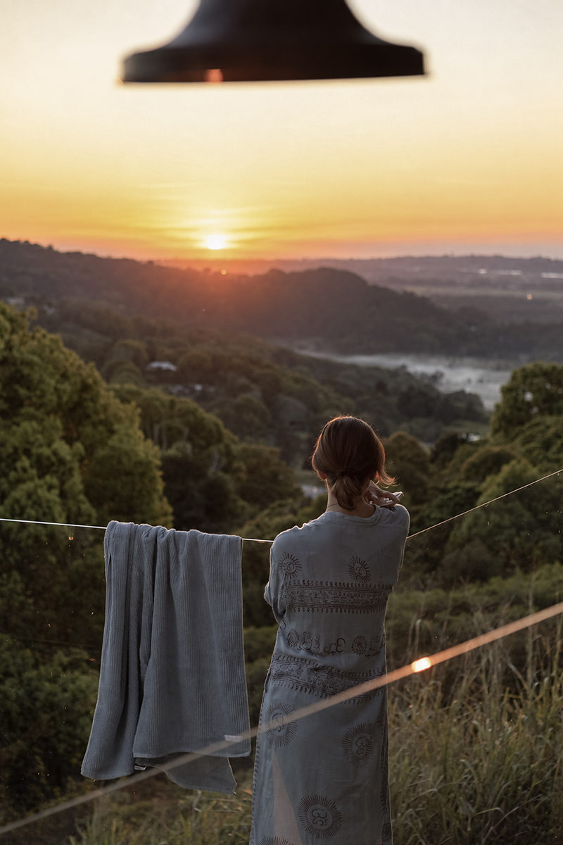 Guest wrapped in a towel looking out at the sunset