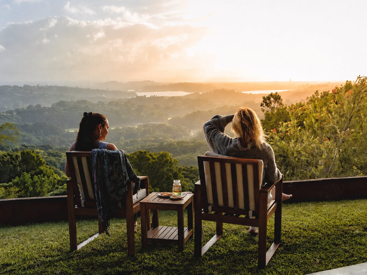 Two guests in timber chairs watching the sun set over the hinterland