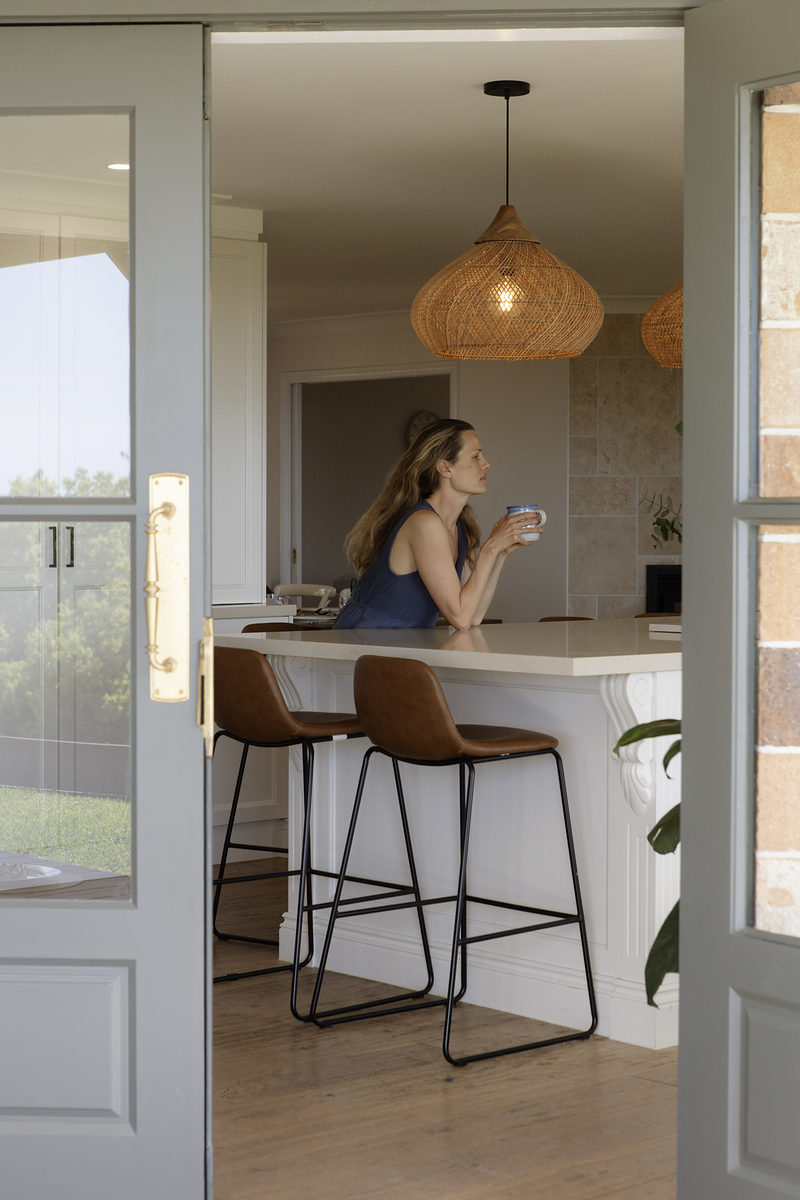 Guest at the kitchen bench seen through the doorway