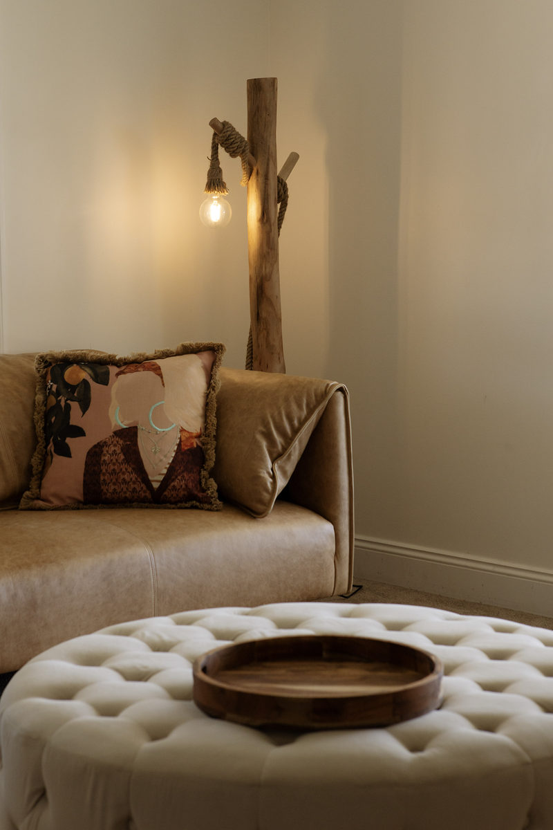Sitting room corner with armchair, ottoman and wall light