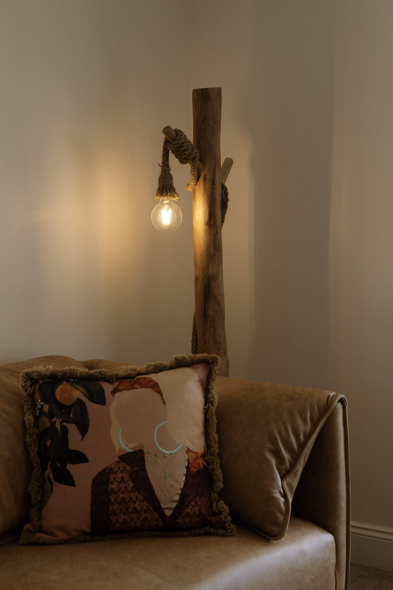 A woven armchair and timber wall light in a quiet corner