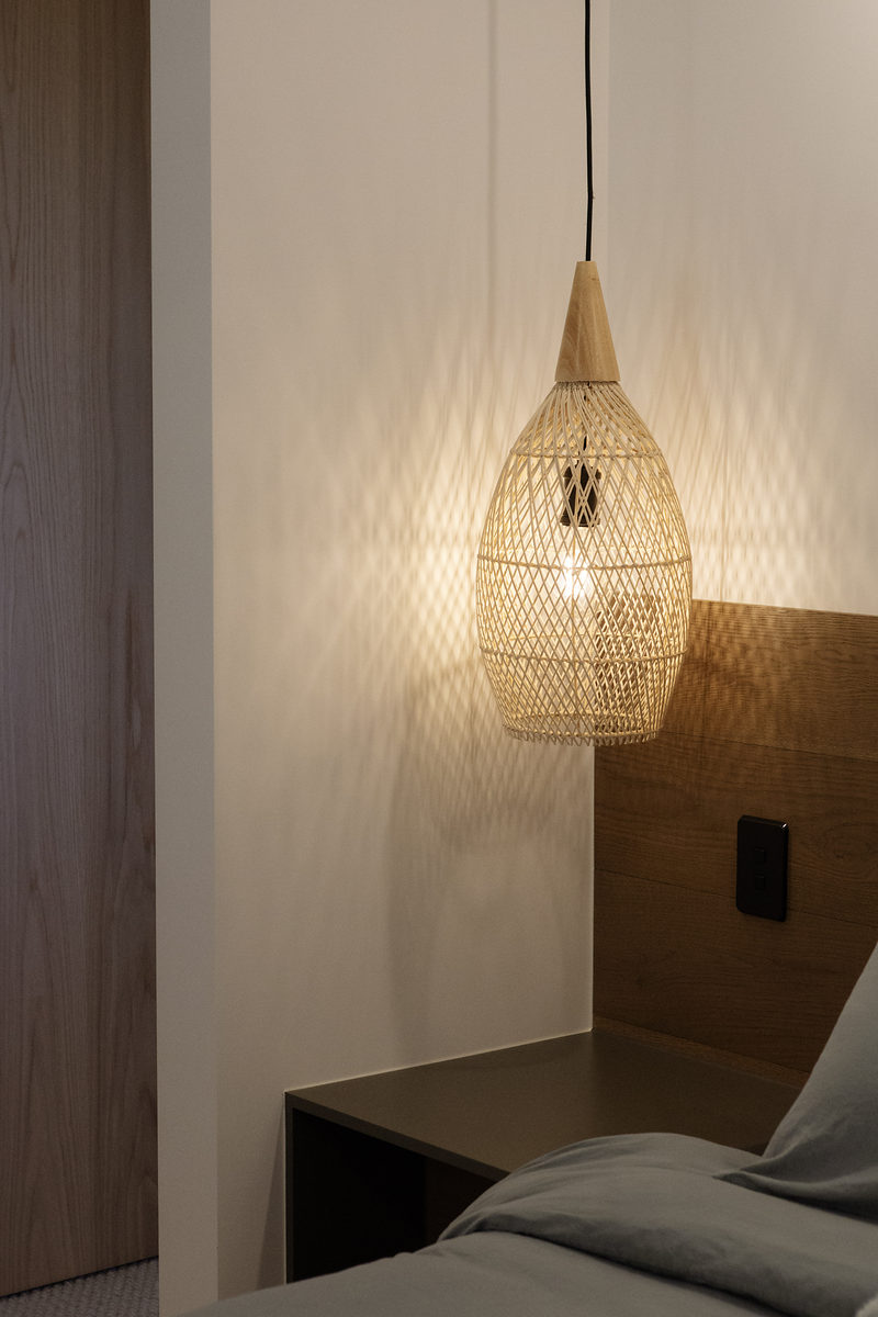 Woven pendant light above a bedside table