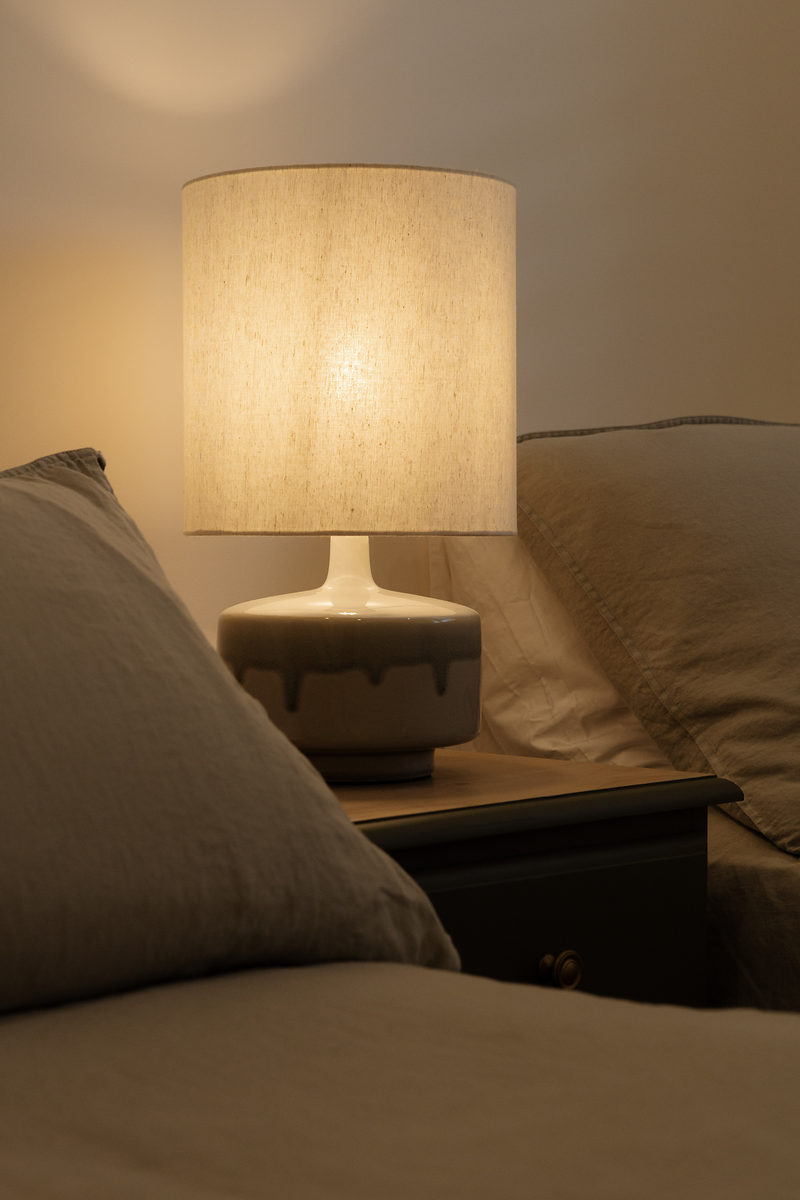 Bedside lamp glowing beside a soft bed