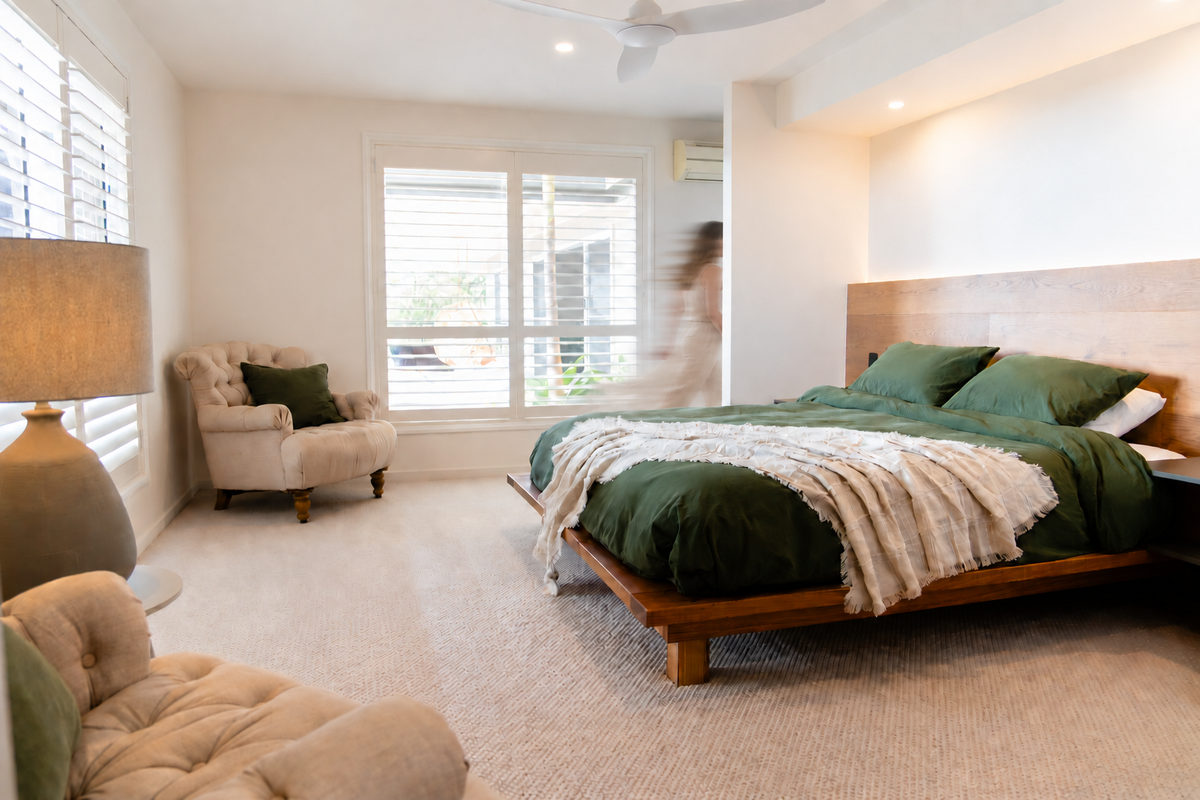 Master bedroom with green linen and a reading chair