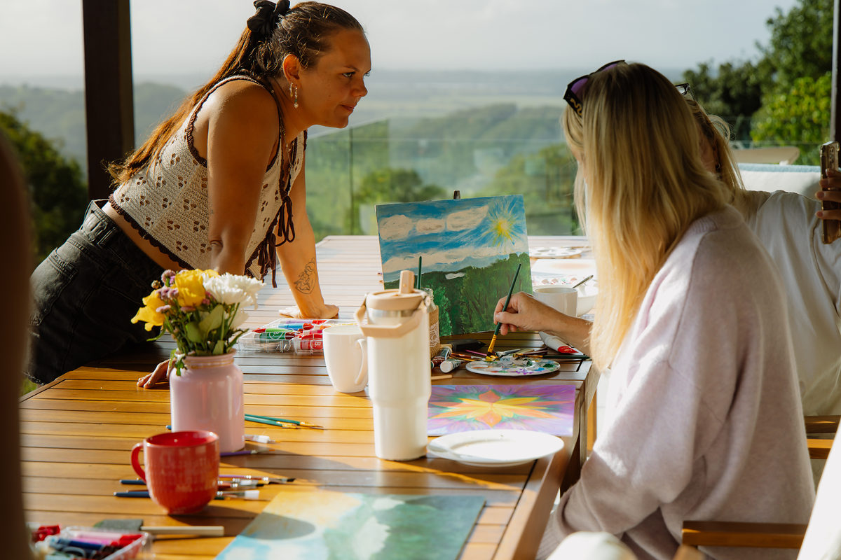 Guests painting together at the outdoor table above the valley