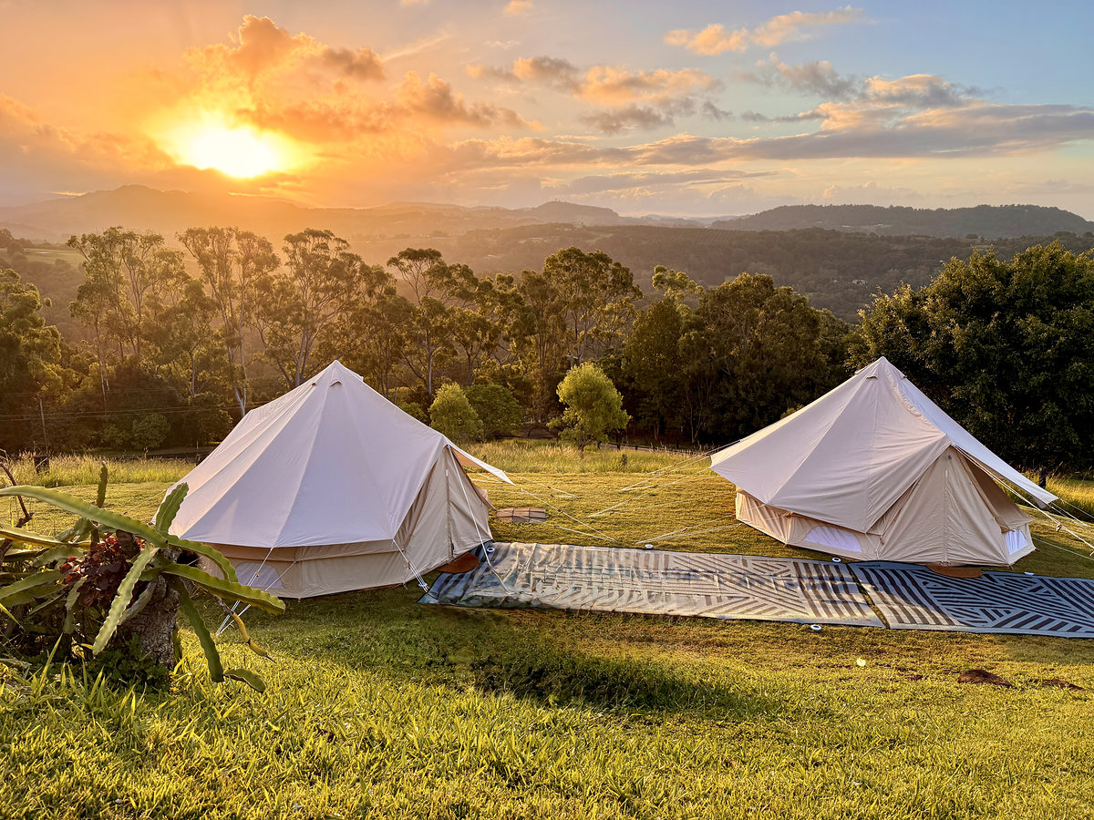 Two glamping tents on the lawn at sunset
