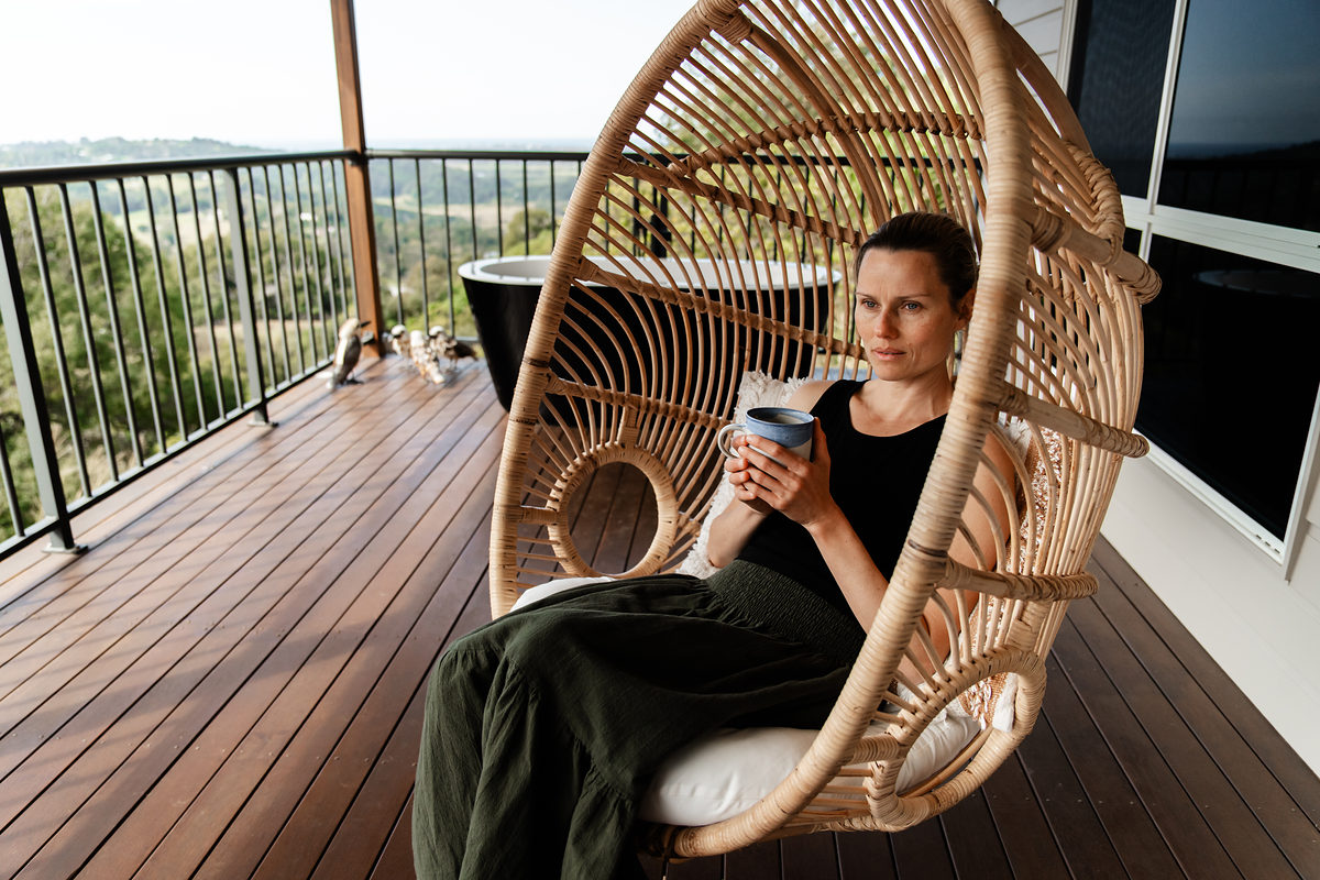 Guest with a coffee in a hanging rattan chair